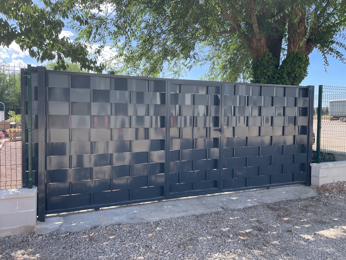 Puerta corredera de chapa entrelazada lacada en gris