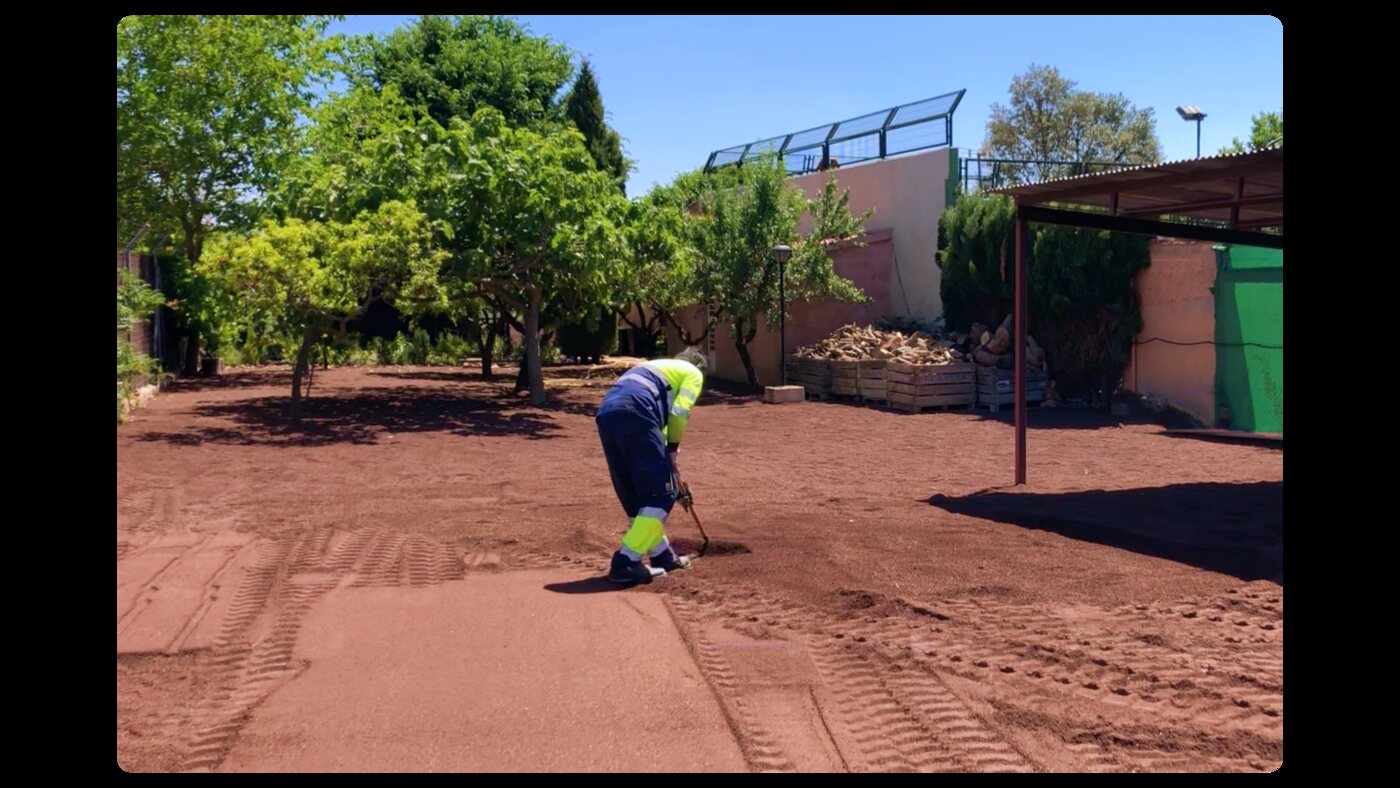 Operario perfilando la zahorra roja antes de la compactación